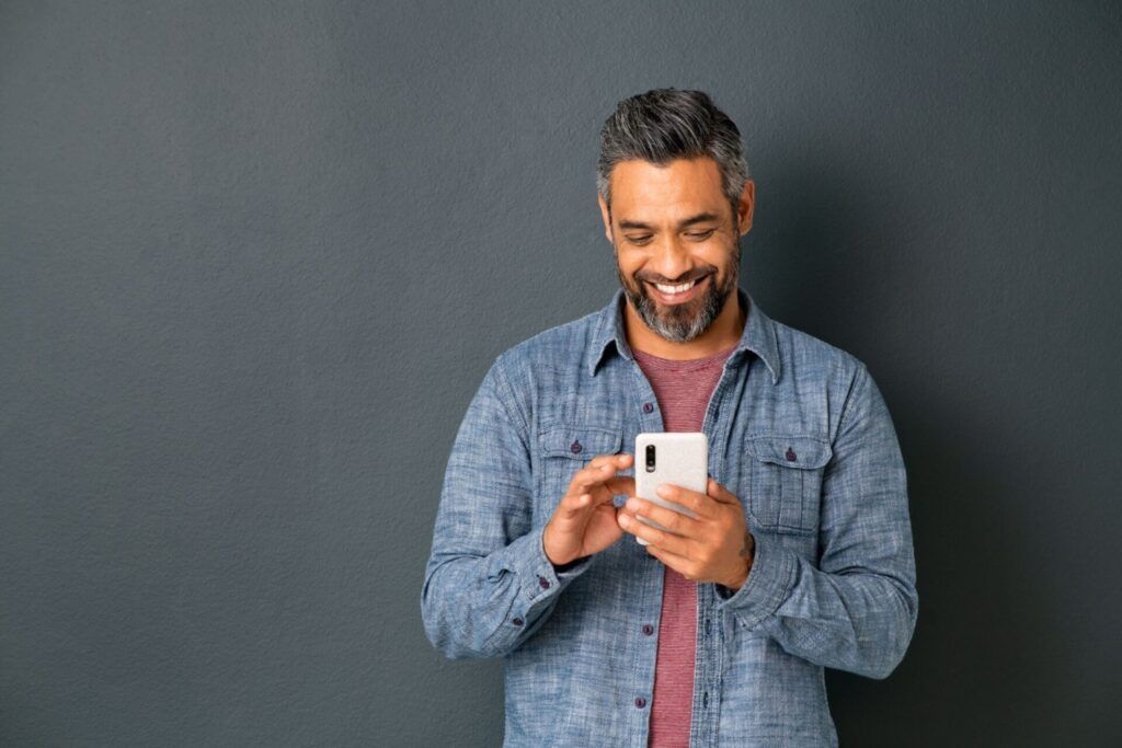 Man smiling while holding a white phone