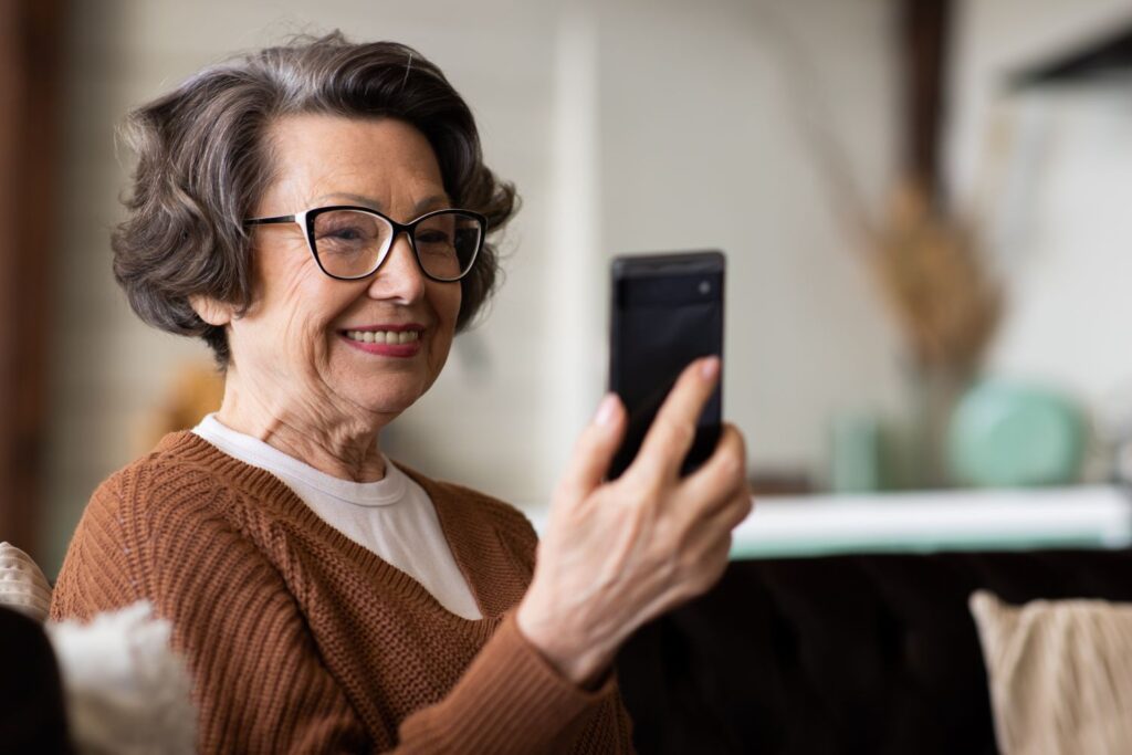 Happy mature middle aged woman enjoying using mobile phone
